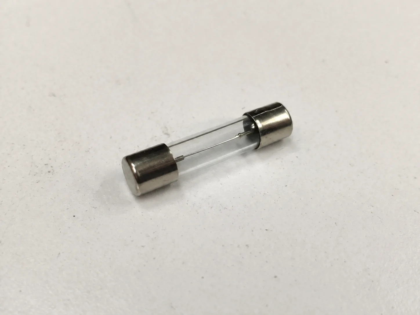 Glass tube current-limiting fuse-link on a laboratory bench for breaking-capacity type testing.
